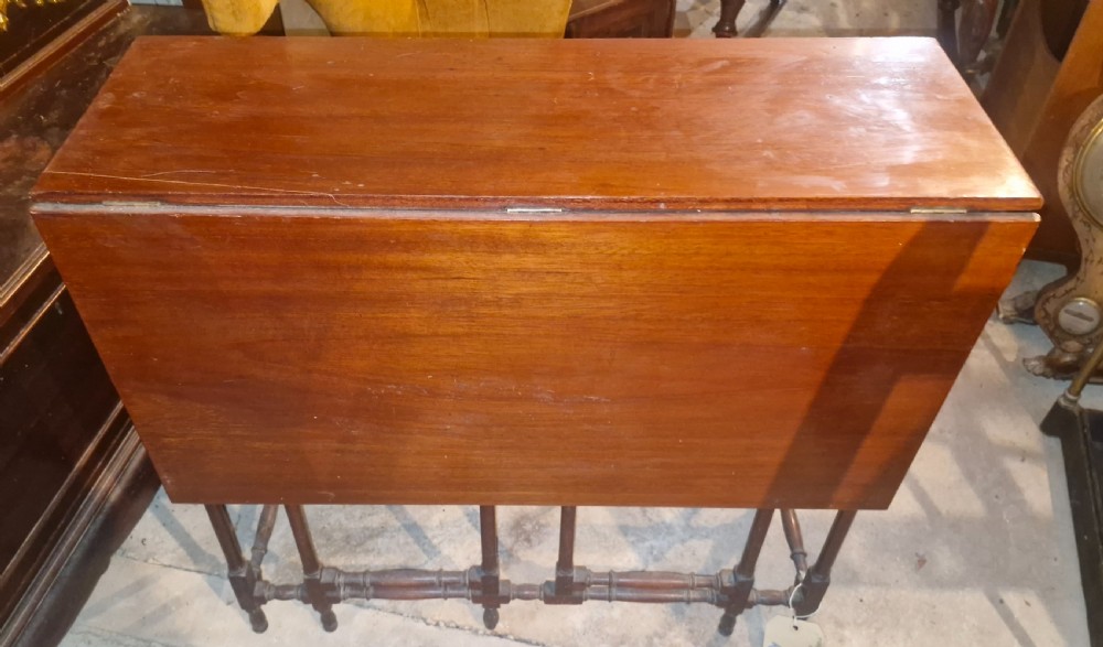 An Edwardian warm brown mahogany double spider gateleg occasional table with folded leaves and slender turned legs.