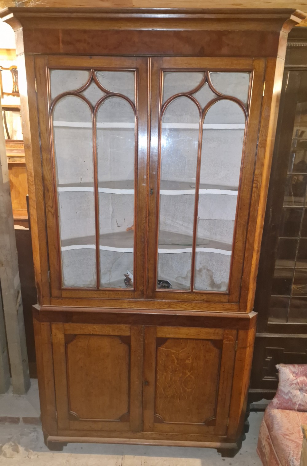 An early Victorian floor-standing Welsh corner cupboard crafted in oak and mahogany, featuring astragal glazed upper doors and solid panelled lower doors. View II