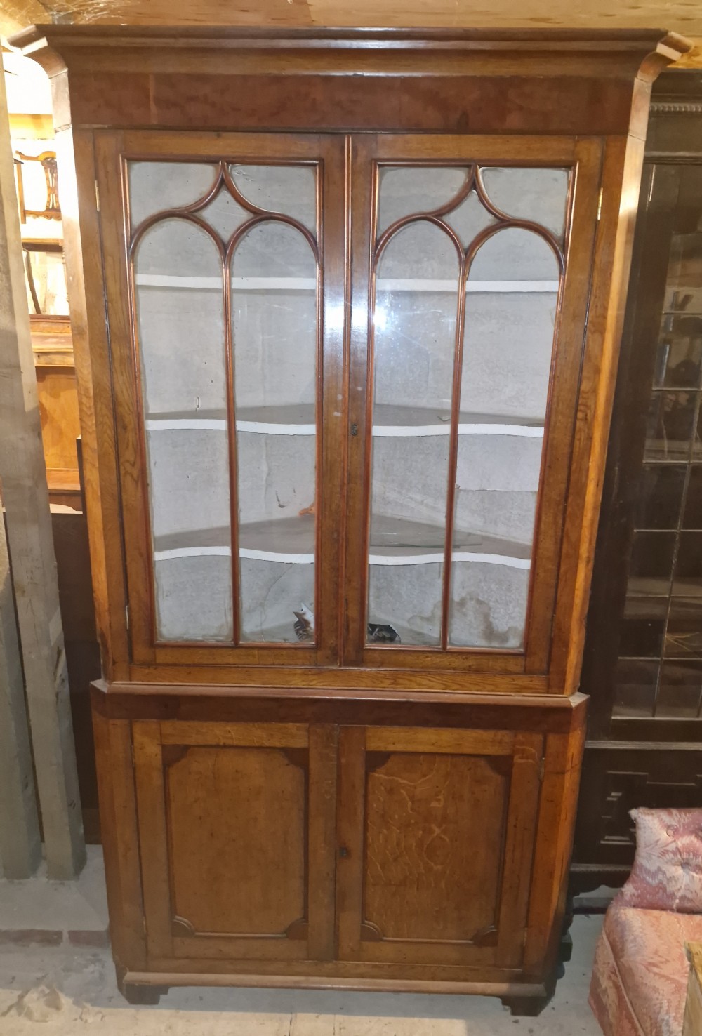 An early Victorian floor-standing Welsh corner cupboard crafted in oak and mahogany, featuring astragal glazed upper doors and solid panelled lower doors. View X