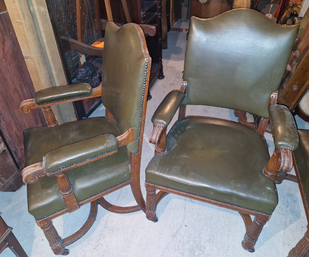 A pair of late Victorian oak desk armchairs upholstered in olive green leather with brass stud detailing and fluted front legs on castors. View II