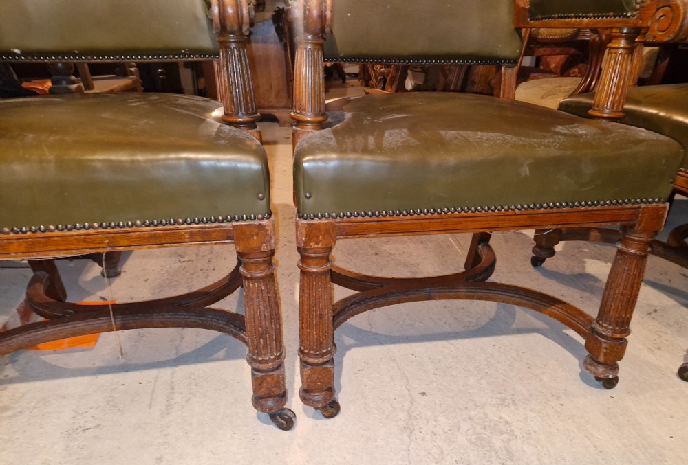 A pair of late Victorian oak desk armchairs upholstered in olive green leather with brass stud detailing and fluted front legs on castors. View IV