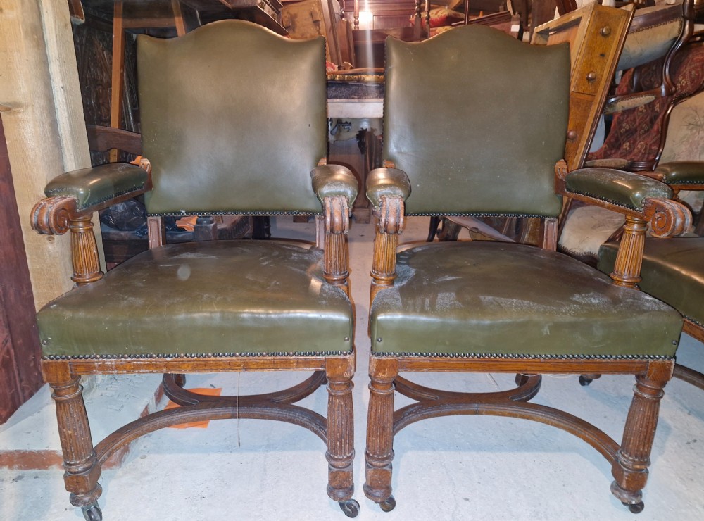 A pair of late Victorian oak desk armchairs upholstered in olive green leather with brass stud detailing and fluted front legs on castors. View VI
