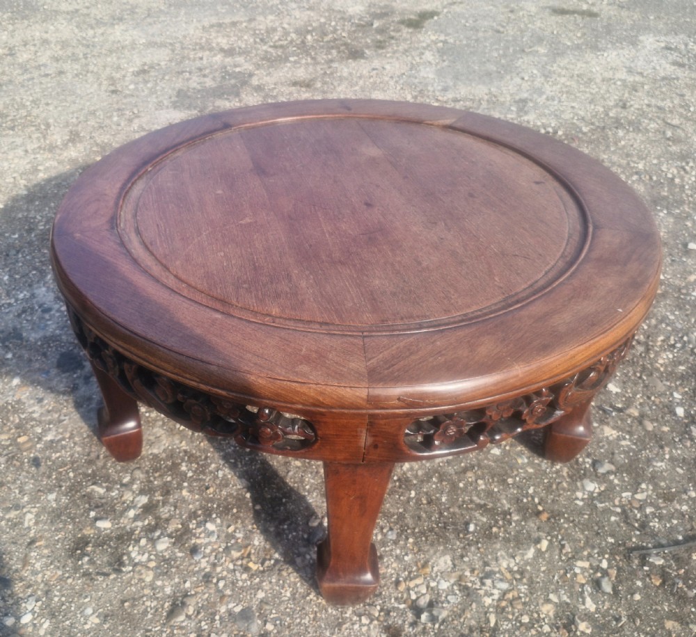 A low circular Chinese hardwood coffee table featuring an intricately carved openwork floral apron and curved legs. View III