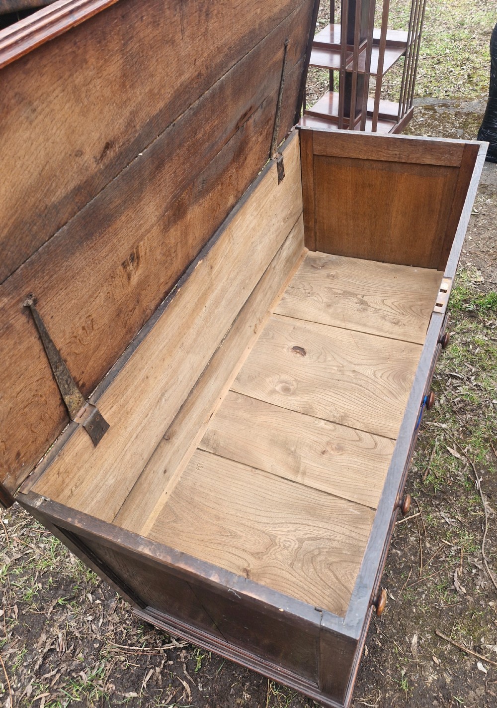 A late Georgian dark oak mule chest featuring a hinged top lid, three front panels, two lower drawers with turned wooden knobs, and bracket feet. View II
