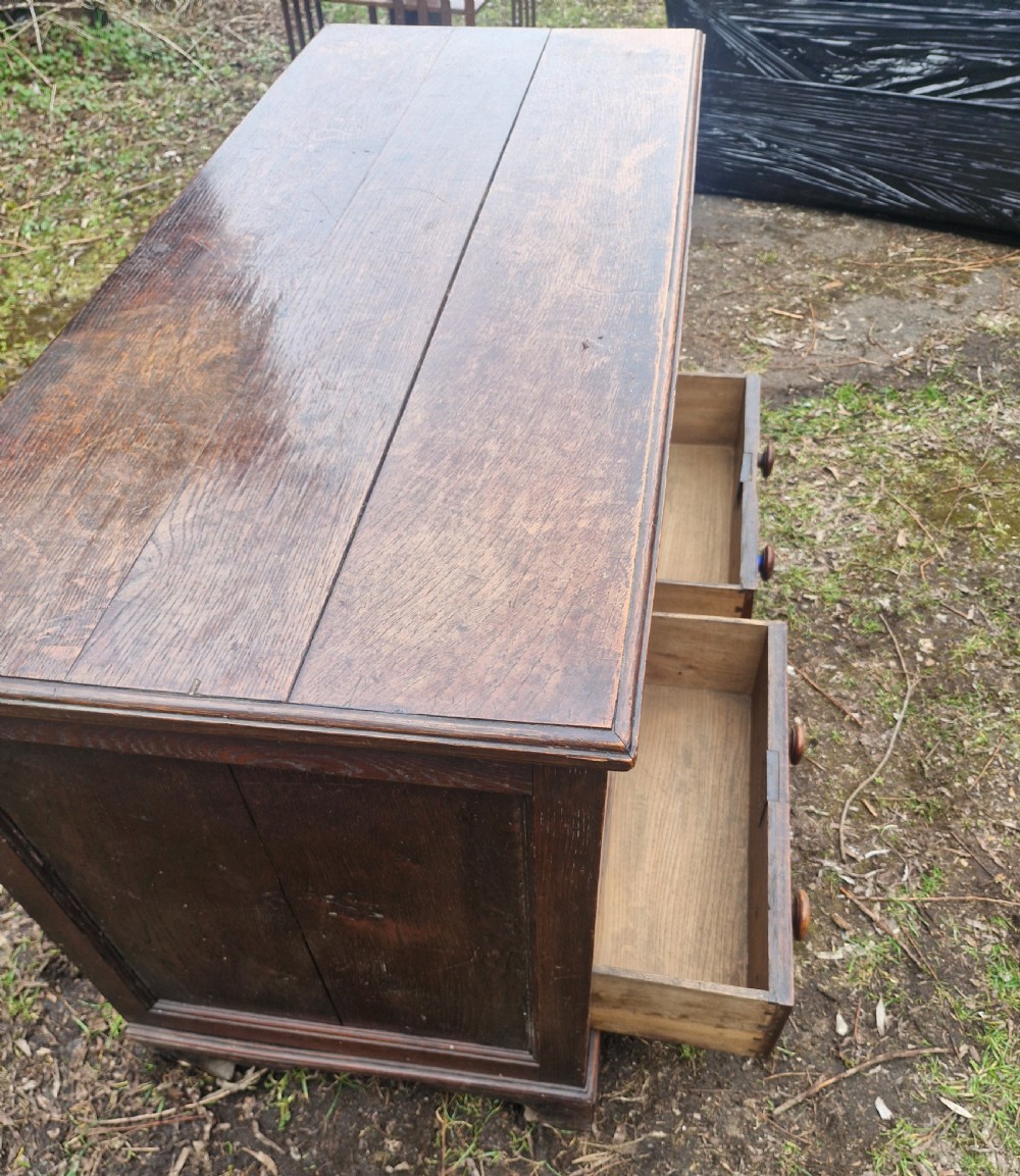 A late Georgian dark oak mule chest featuring a hinged top lid, three front panels, two lower drawers with turned wooden knobs, and bracket feet. View IV