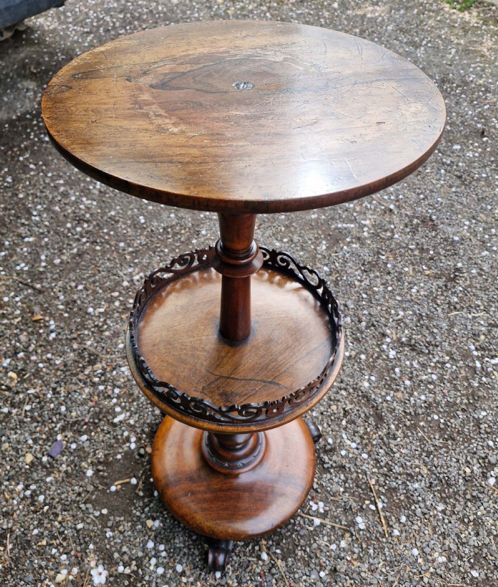 An early Victorian rosewood decanter table featuring a circular top, a central turned stem with a fretwork-gallery lower tier, and a circular base with scroll feet. View II