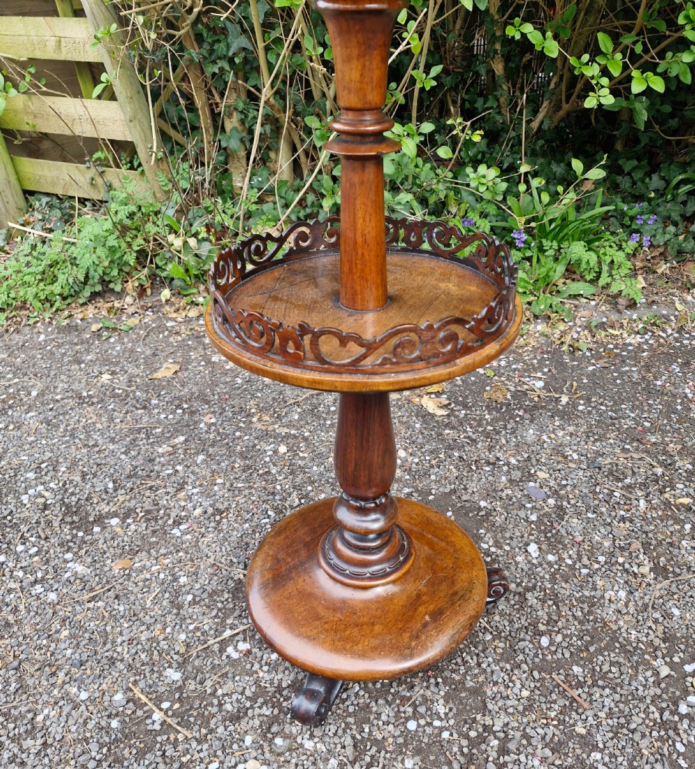 An early Victorian rosewood decanter table featuring a circular top, a central turned stem with a fretwork-gallery lower tier, and a circular base with scroll feet. View III