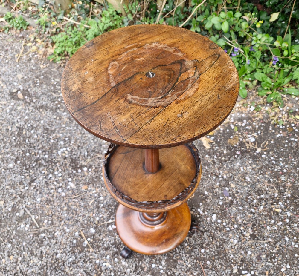 An early Victorian rosewood decanter table featuring a circular top, a central turned stem with a fretwork-gallery lower tier, and a circular base with scroll feet. View VI