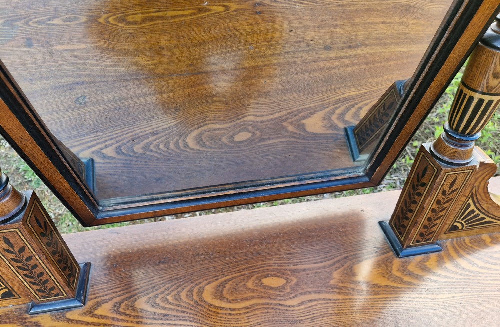 A late Victorian warm brown wood pedestal dressing table featuring ebonised stencilled accents, turned mirror supports, and nine drawers flanking a central kneehole. View IV