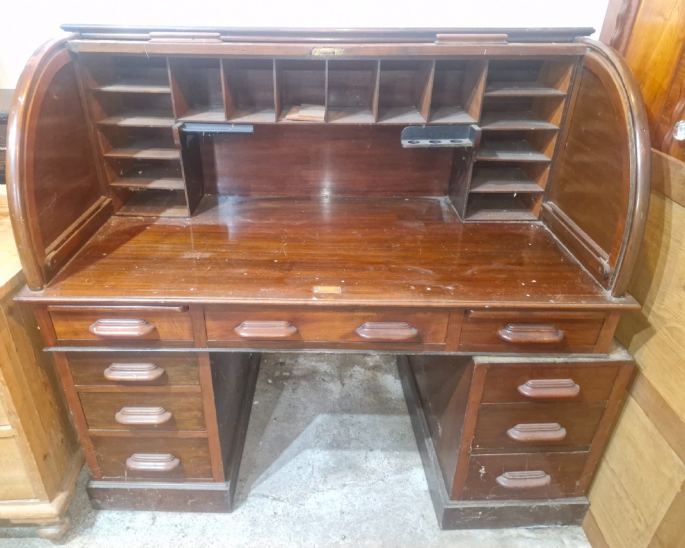 A large mahogany pedestal desk featuring a flexible slatted tambour roll-top hood above multiple drawers with carved wood pulls. View VII