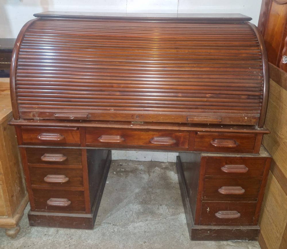 A large mahogany pedestal desk featuring a flexible slatted tambour roll-top hood above multiple drawers with carved wood pulls. View VIII
