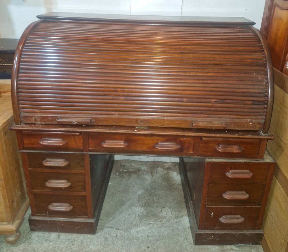 A large mahogany pedestal desk featuring a flexible slatted tambour roll-top hood above multiple drawers with carved wood pulls. View IX