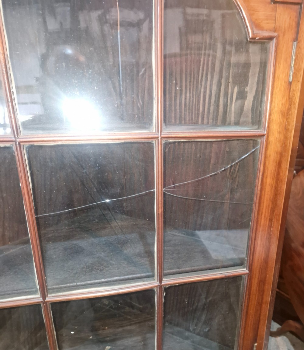 A tall early 20th-century walnut corner display cabinet featuring two sections, arched glazed doors, and a shaped pediment top. View VI