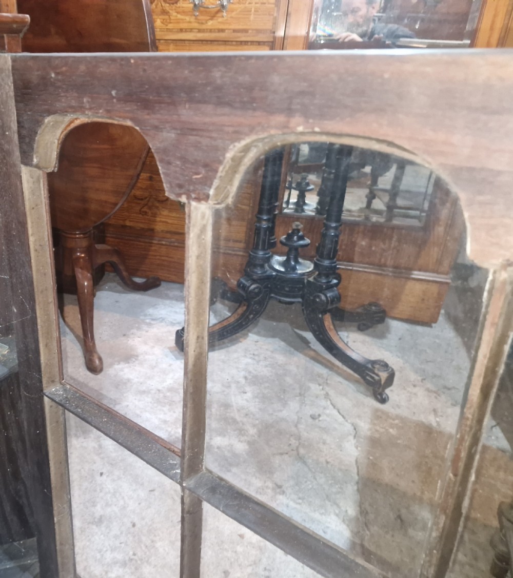 A tall early 20th-century walnut corner display cabinet featuring two sections, arched glazed doors, and a shaped pediment top. View VII