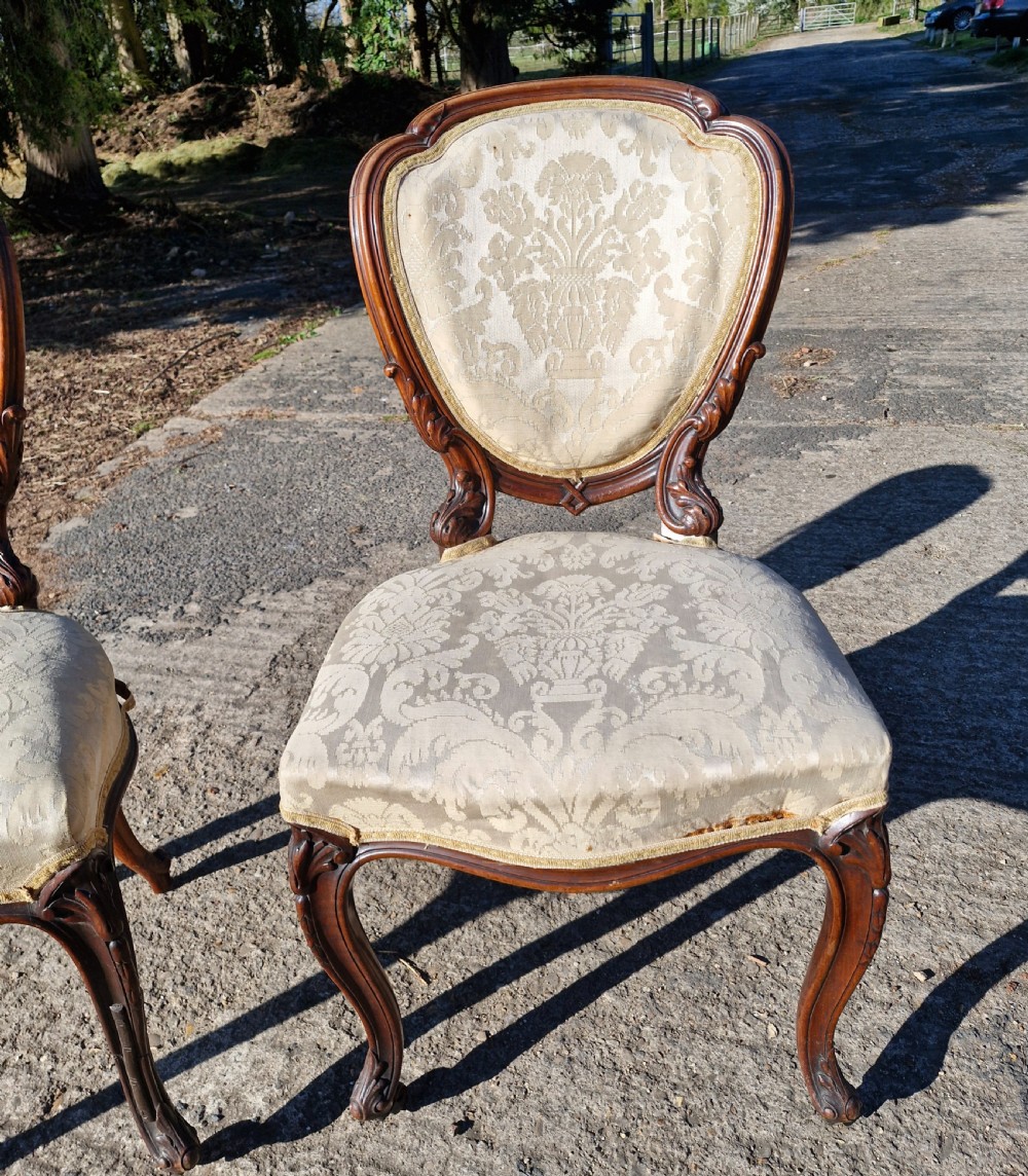 A pair of 19th-century Rococo Revival side chairs with carved dark wood frames, cabriole legs, and cream damask upholstered seats and backrests. View VIII