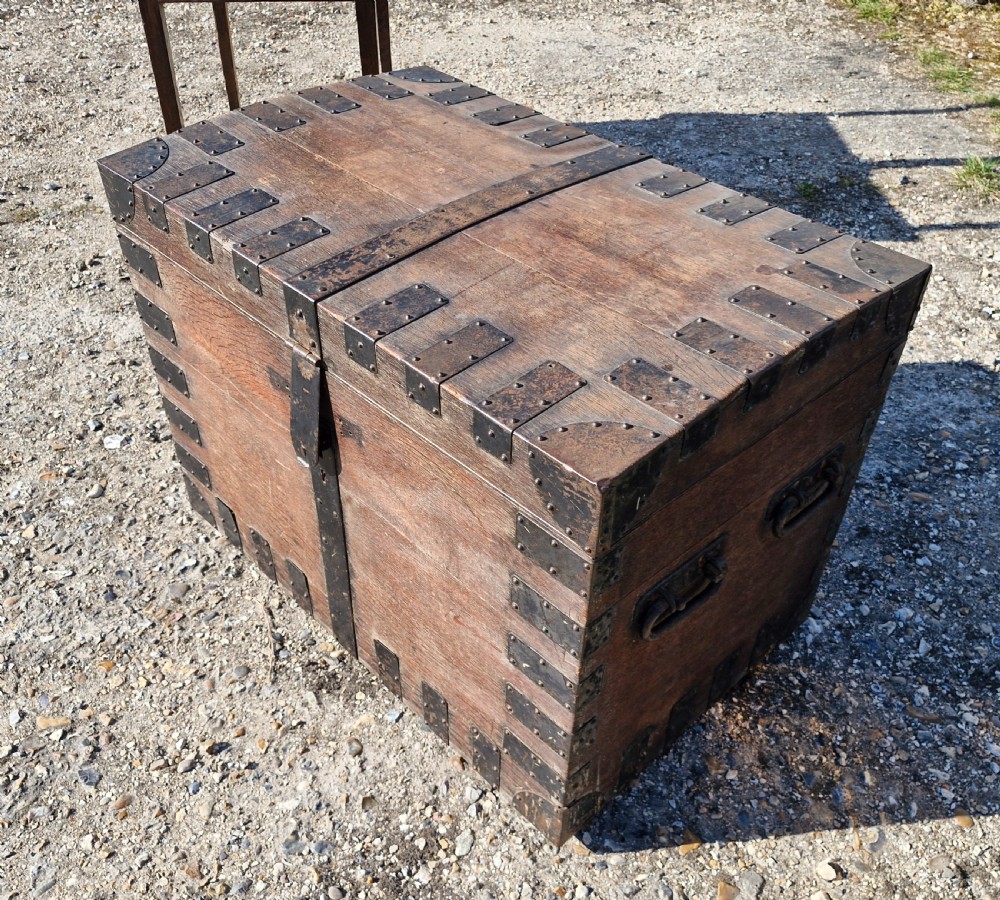 A rectangular Victorian oak chest with dark metal corner brackets, iron straps, stud detailing, and side handles.