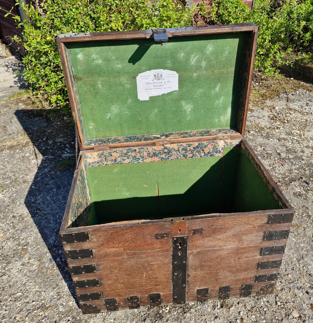 A rectangular Victorian oak chest with dark metal corner brackets, iron straps, stud detailing, and side handles. View VI