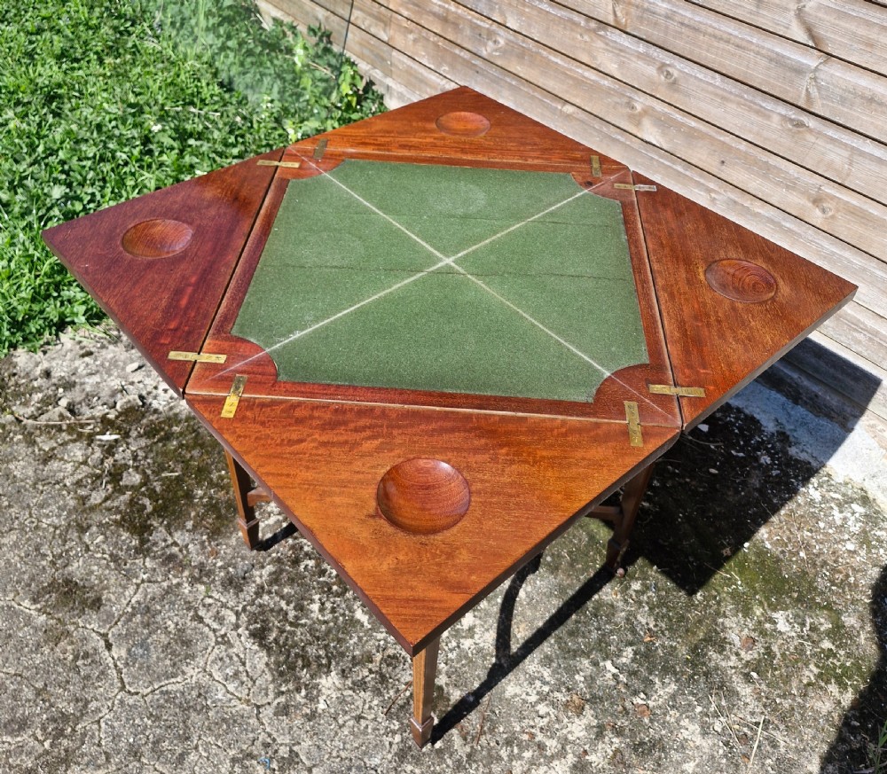 An Edwardian square mahogany envelope games table featuring foliate marquetry inlay, a single drawer with brass drop handles, a lower undertier, and tapered legs. View III