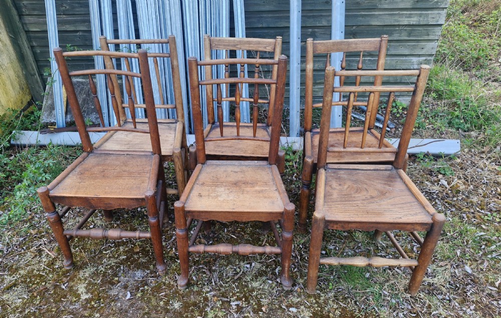 A set of six early nineteenth-century country wooden dining chairs featuring spindle backrests, solid timber seats, and turned legs with stretchers.