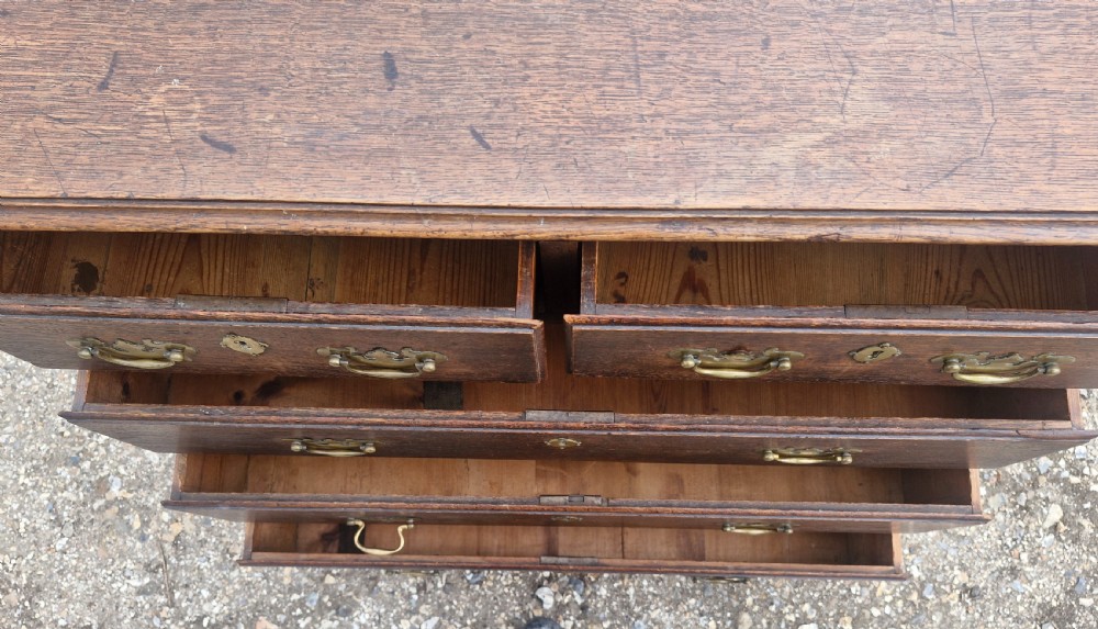 A dark oak Georgian chest of drawers featuring a two-over-three drawer arrangement, decorative brass handles, keyholes, and bracket feet. View II