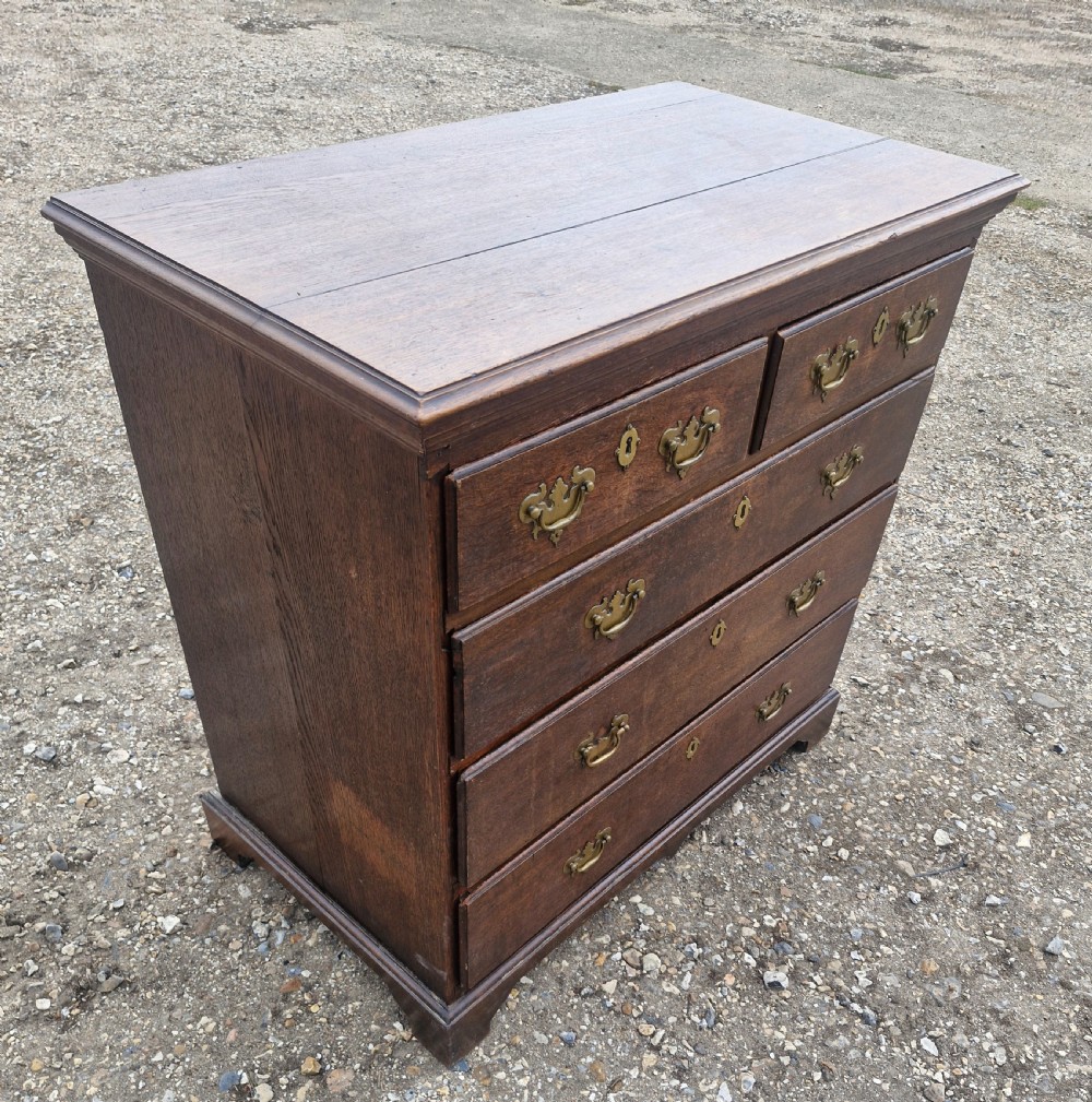 A dark oak Georgian chest of drawers featuring a two-over-three drawer arrangement, decorative brass handles, keyholes, and bracket feet. View III