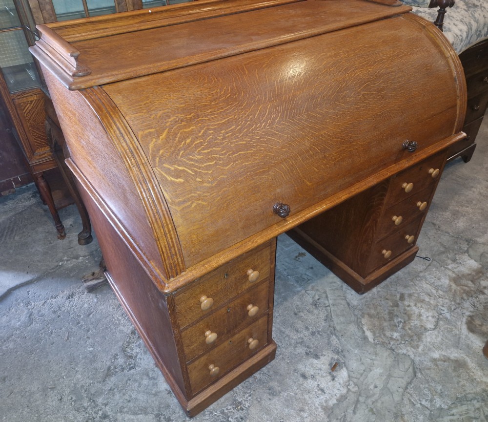 A Victorian oak cylinder top writing desk featuring a curved roll-down front and twin drawer pedestals. View XV