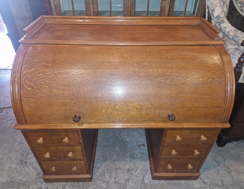 A Victorian oak cylinder top writing desk featuring a curved roll-down front and twin drawer pedestals. View XVI