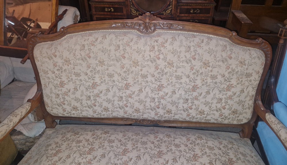A small French Louis XV style two-seater sofa with a carved walnut frame, cabriole legs, floral top cresting, and patterned beige textile upholstery. View VI
