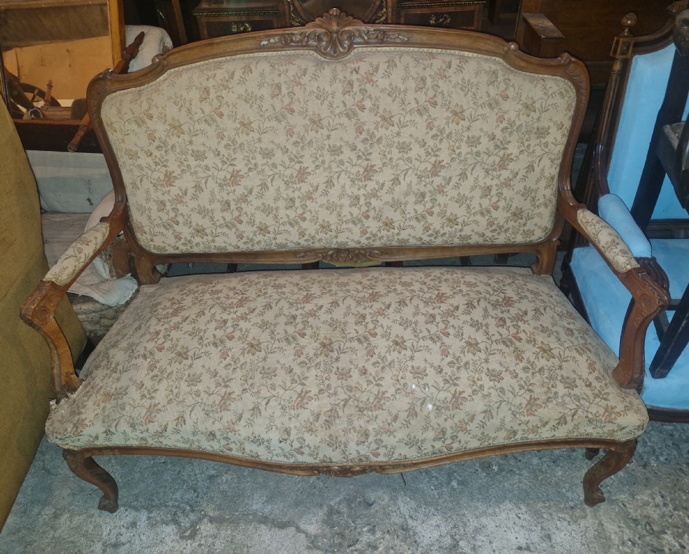 A small French Louis XV style two-seater sofa with a carved walnut frame, cabriole legs, floral top cresting, and patterned beige textile upholstery. View IX