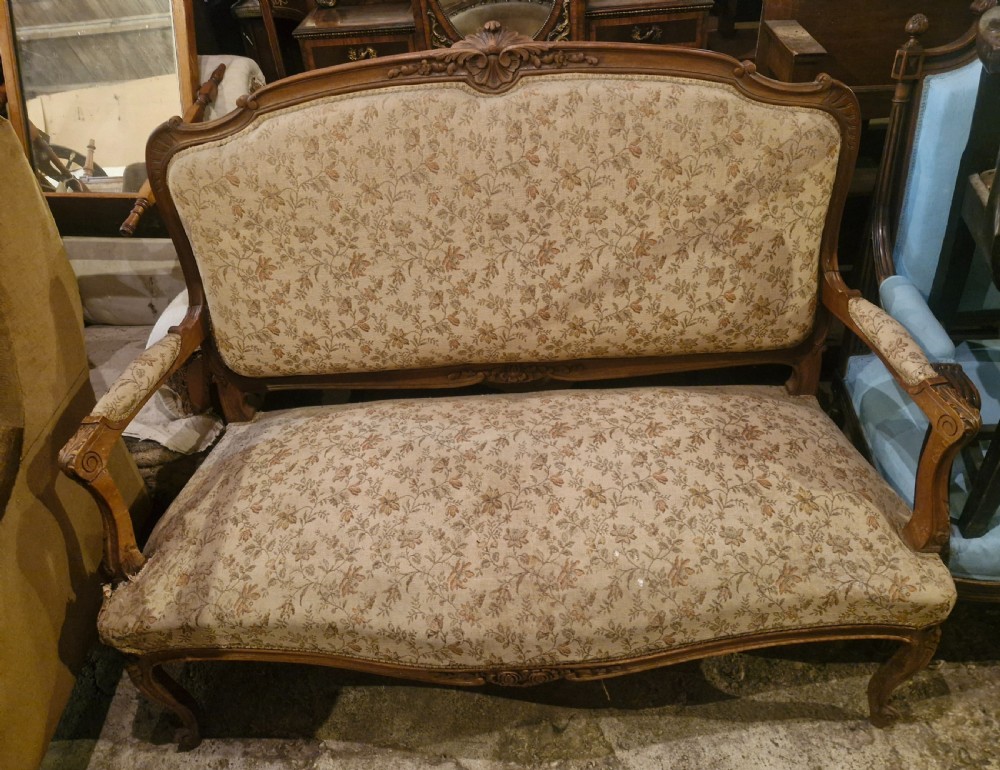 A small French Louis XV style two-seater sofa with a carved walnut frame, cabriole legs, floral top cresting, and patterned beige textile upholstery. View XII
