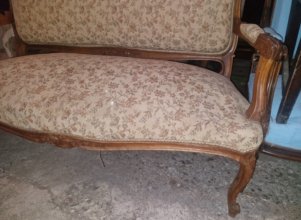 A small French Louis XV style two-seater sofa with a carved walnut frame, cabriole legs, floral top cresting, and patterned beige textile upholstery. View XIV