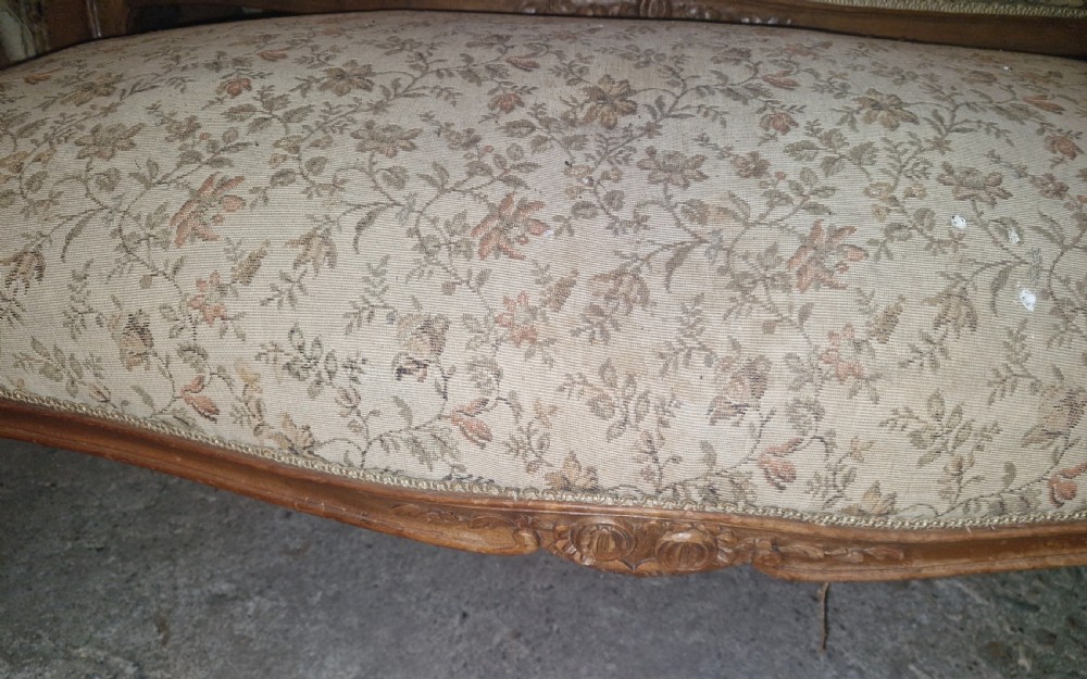 A small French Louis XV style two-seater sofa with a carved walnut frame, cabriole legs, floral top cresting, and patterned beige textile upholstery. View XV