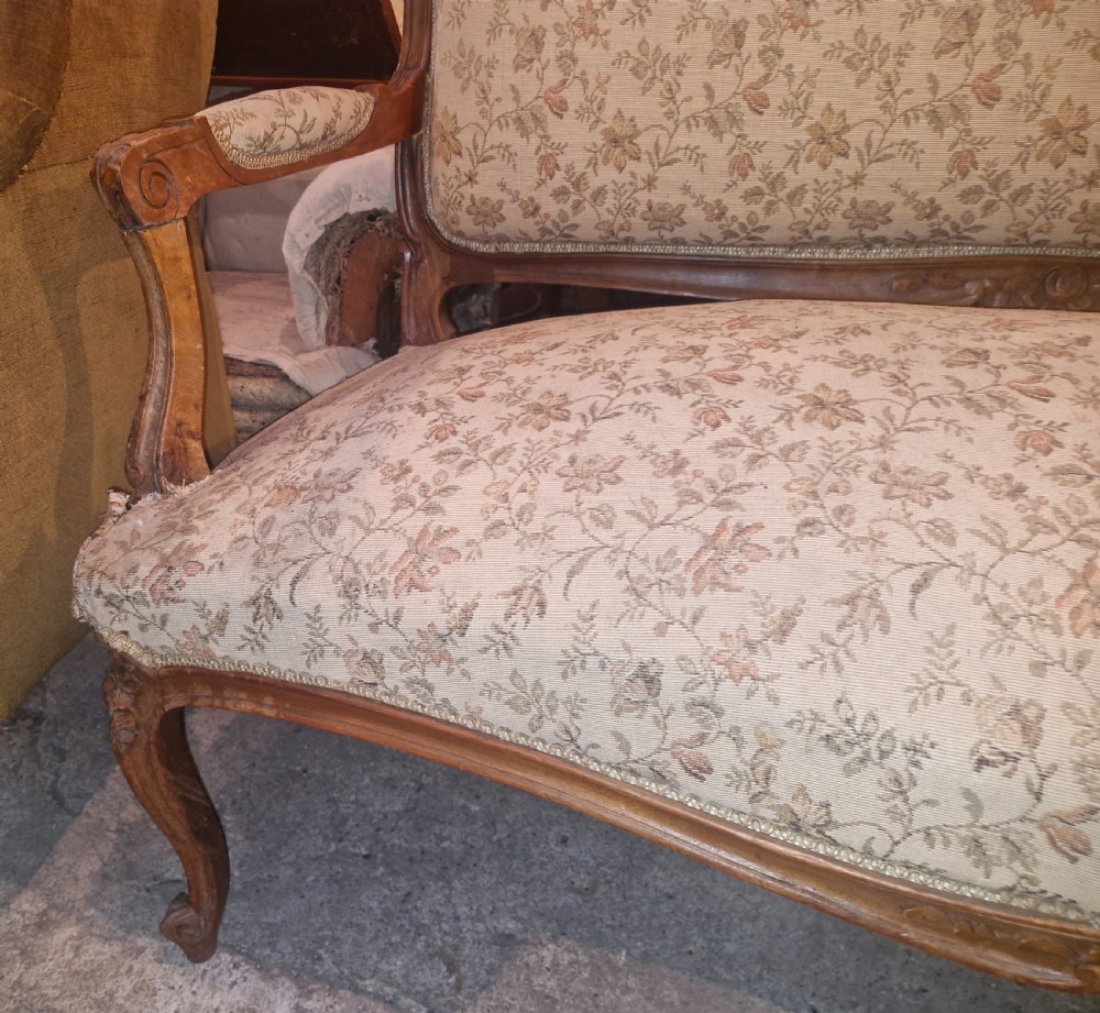 A small French Louis XV style two-seater sofa with a carved walnut frame, cabriole legs, floral top cresting, and patterned beige textile upholstery. View XVII