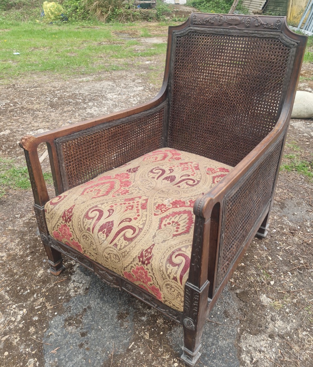 An Edwardian mahogany bergere armchair with woven cane panels on the back and sides and a patterned upholstery seat cushion. View II
