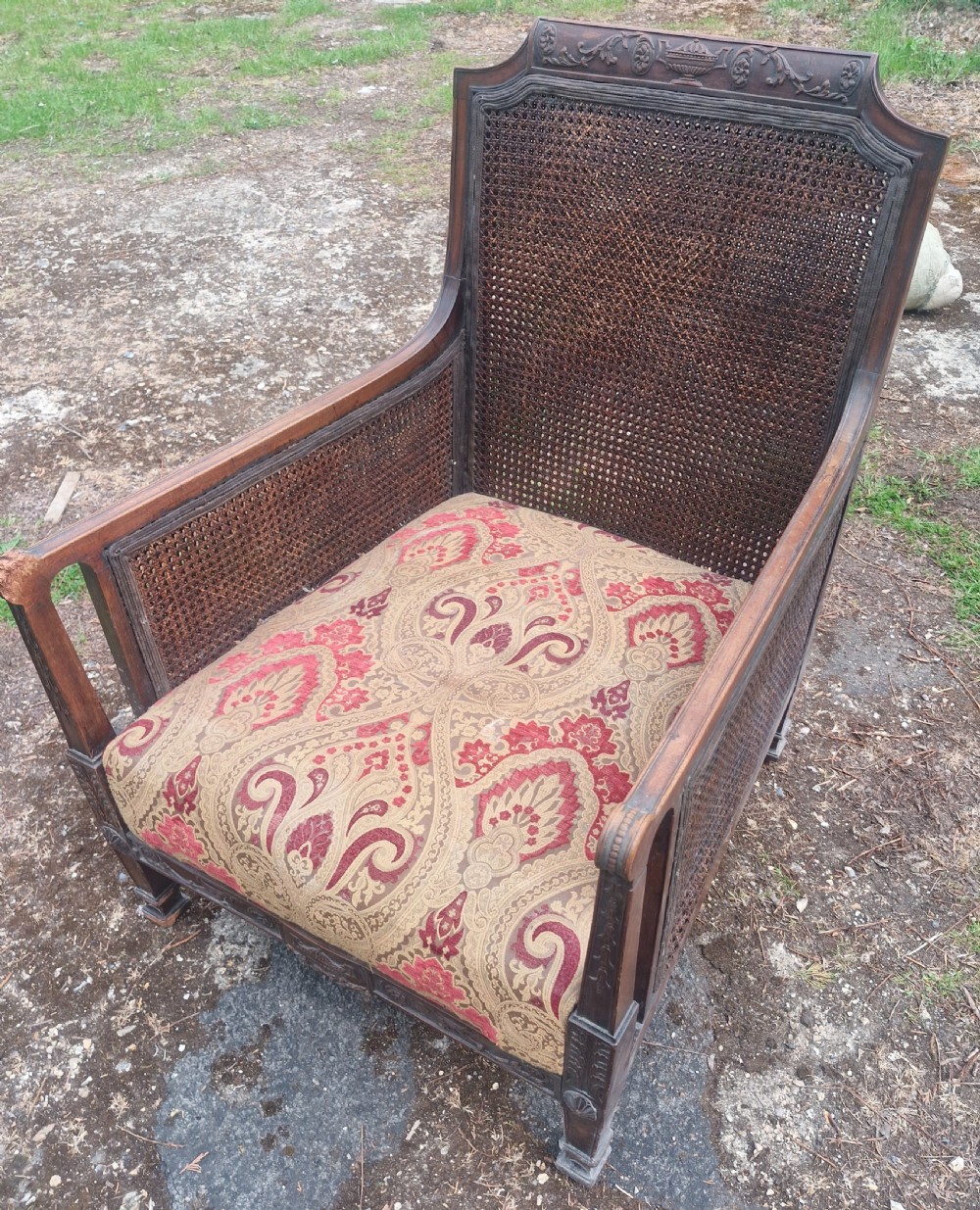 An Edwardian mahogany bergere armchair with woven cane panels on the back and sides and a patterned upholstery seat cushion. View VIII