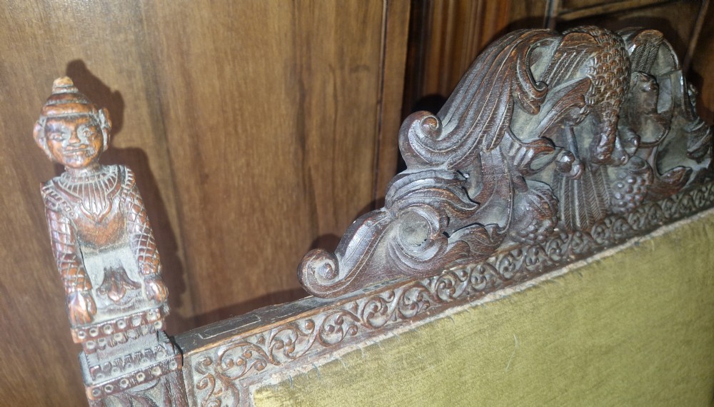A detailed carved dark wood Anglo-Indian armchair featuring an elephant motif cresting, figural finials, and olive green velvet seat and back upholstery. View XIV