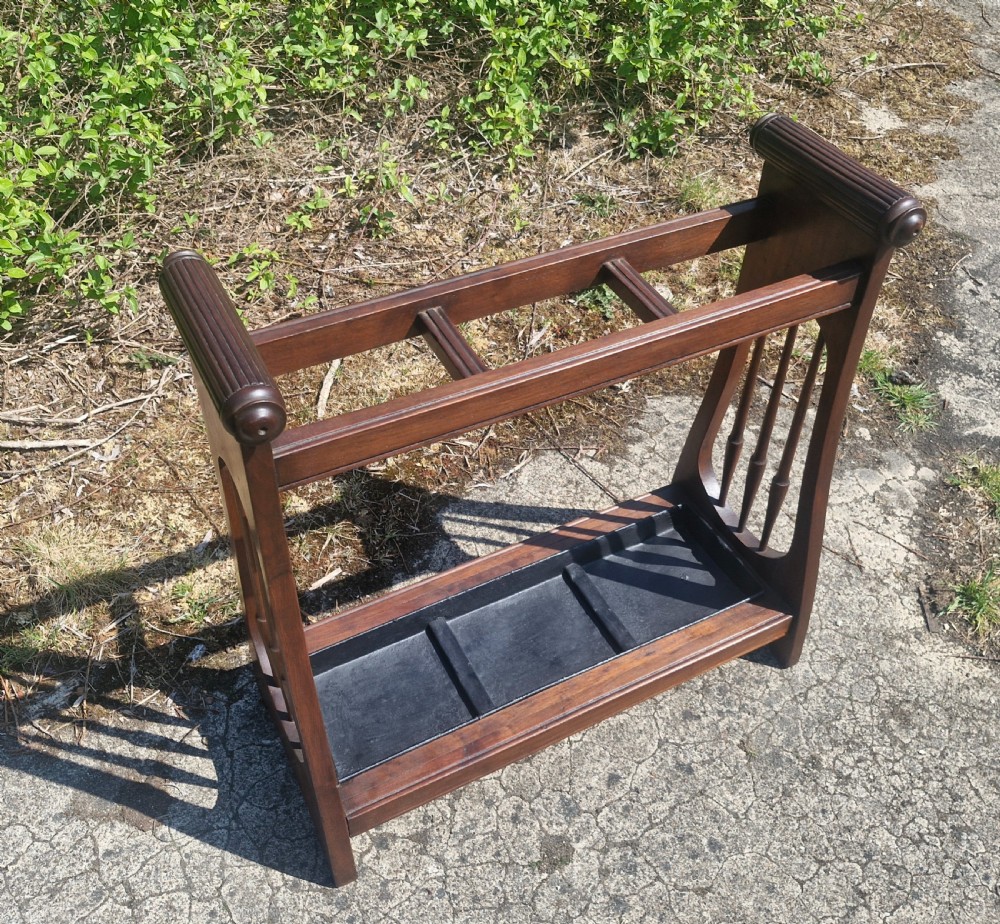 A late Victorian mahogany umbrella and stick stand featuring turned side spindles, reeded end handles, divided upper sections, and a black cast iron drip tray. View II