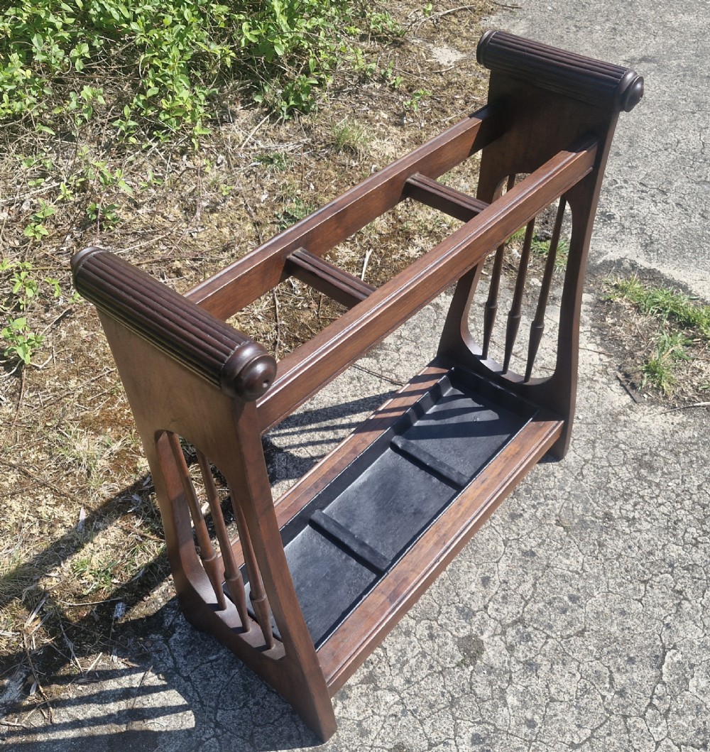 A late Victorian mahogany umbrella and stick stand featuring turned side spindles, reeded end handles, divided upper sections, and a black cast iron drip tray. View VI