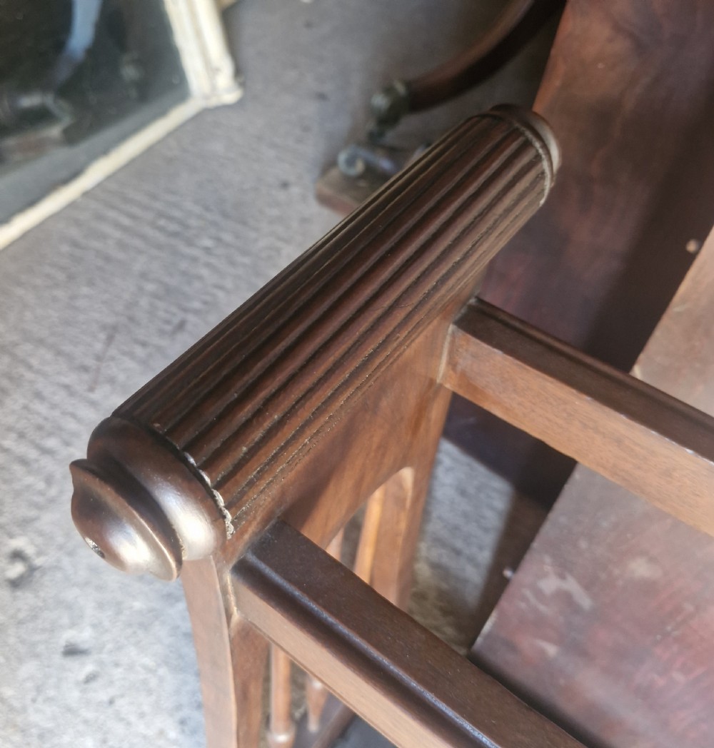A late Victorian mahogany umbrella and stick stand featuring turned side spindles, reeded end handles, divided upper sections, and a black cast iron drip tray. View VIII