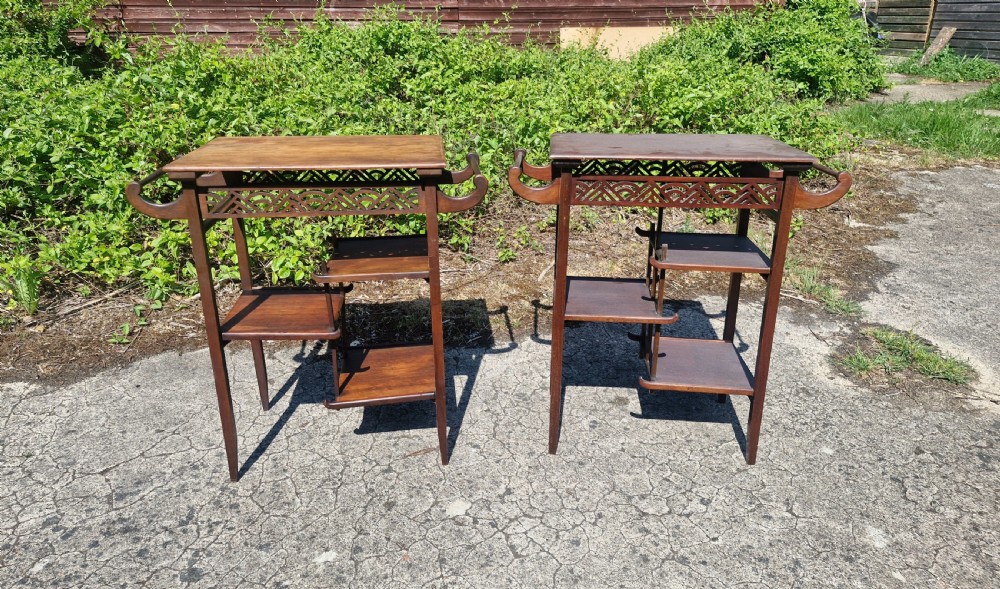 A pair of mahogany Anglo-Japanese occasional tables featuring pierced fretwork friezes, side handles, and staggered lower shelves. View II