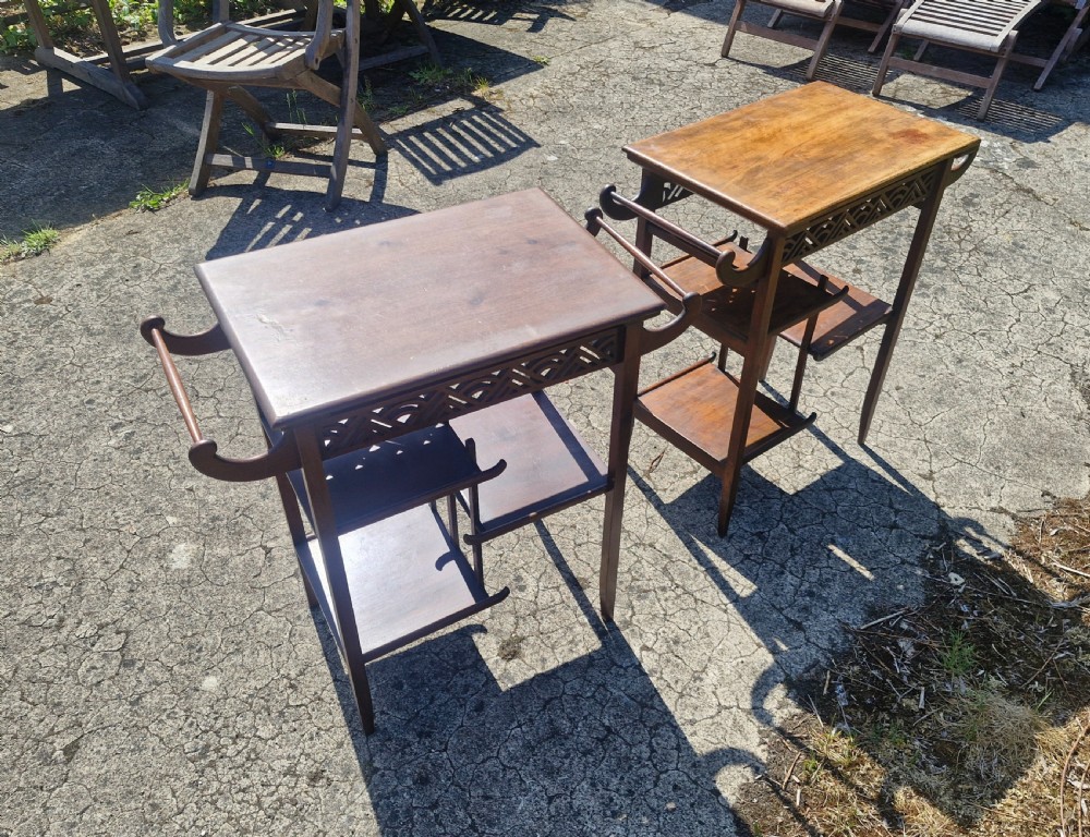 A pair of mahogany Anglo-Japanese occasional tables featuring pierced fretwork friezes, side handles, and staggered lower shelves. View V