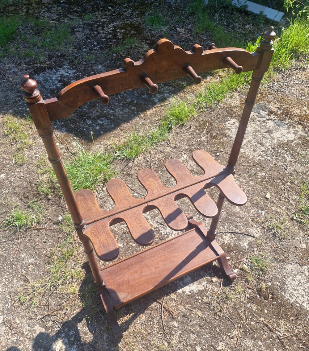 A Regency mahogany boot and whip stand featuring upper pegs, carved boot slots, turned uprights, and a trestle base. View VI
