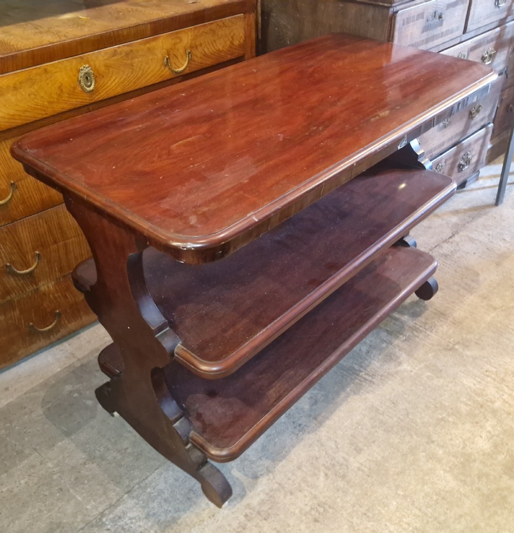 A mid-19th-century mahogany three-tier etagere featuring rounded rectangular shelves supported by carved S-scroll uprights.
