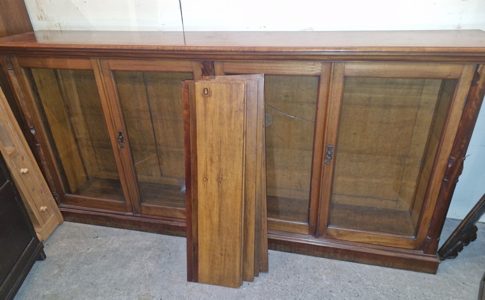 A large late Victorian mahogany low bookcase featuring four glazed glass doors with removable timber shelves resting in front.