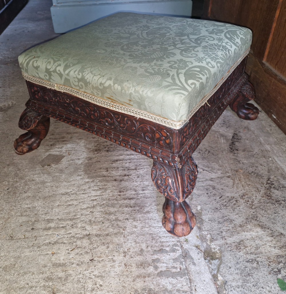 A square Anglo-Indian footstool featuring a green damask upholstered top above a deeply carved dark hardwood frame with claw feet. View III