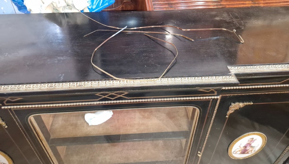 A Victorian ebonised three-door credenza featuring a central glazed compartment flanked by panelled doors decorated with oval hand-painted porcelain plaques and gilt metal mounts. View II