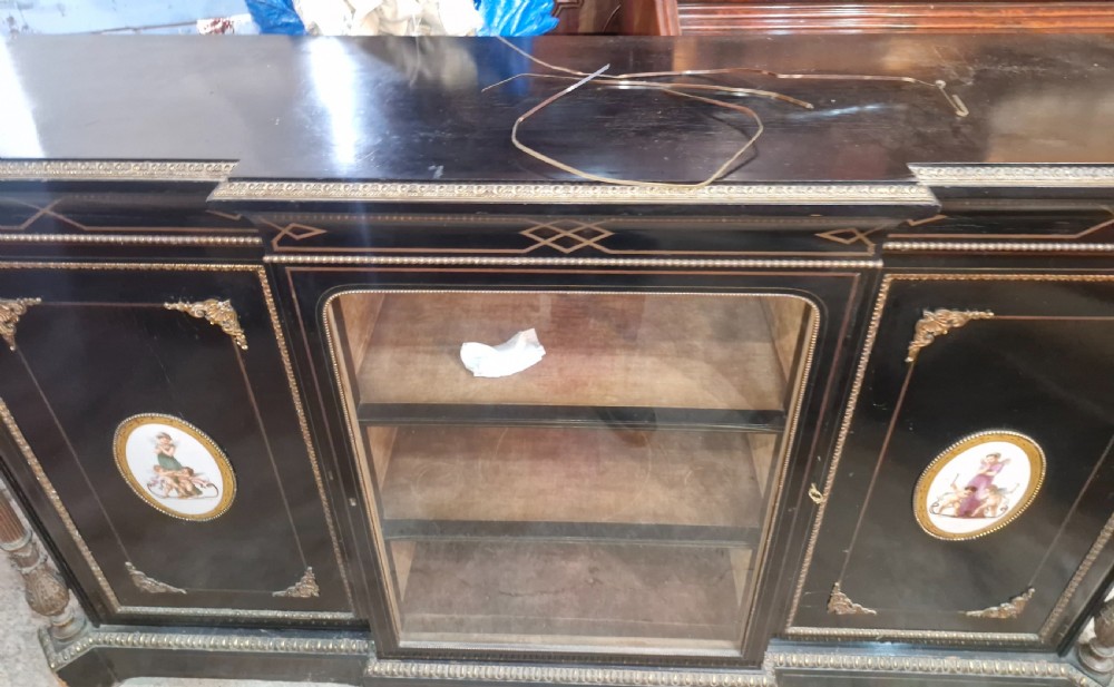 A Victorian ebonised three-door credenza featuring a central glazed compartment flanked by panelled doors decorated with oval hand-painted porcelain plaques and gilt metal mounts. View III