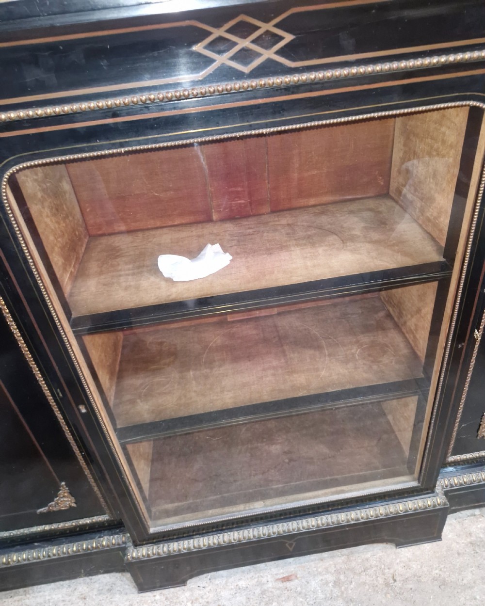 A Victorian ebonised three-door credenza featuring a central glazed compartment flanked by panelled doors decorated with oval hand-painted porcelain plaques and gilt metal mounts. View VII