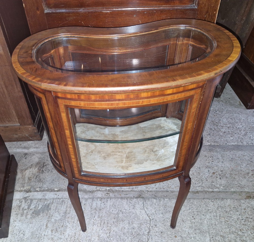 An Edwardian kidney-shaped mahogany bijouterie display cabinet featuring glass panels, marquetry inlay, and cabriole legs. View II