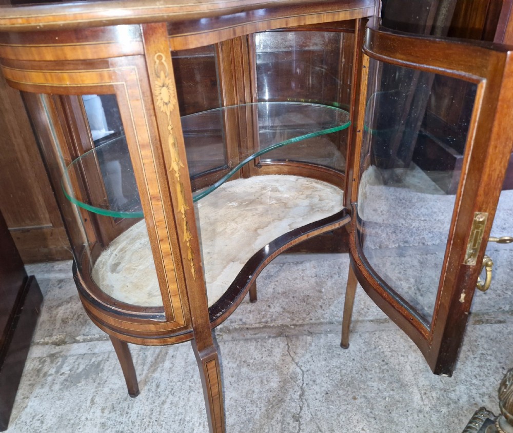 An Edwardian kidney-shaped mahogany bijouterie display cabinet featuring glass panels, marquetry inlay, and cabriole legs. View III